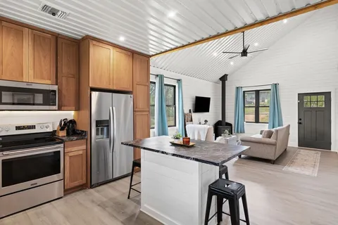 a kitchen with stainless steel appliances granite countertop a refrigerator a stove a sink dishwasher a dining table and chairs with wooden floor