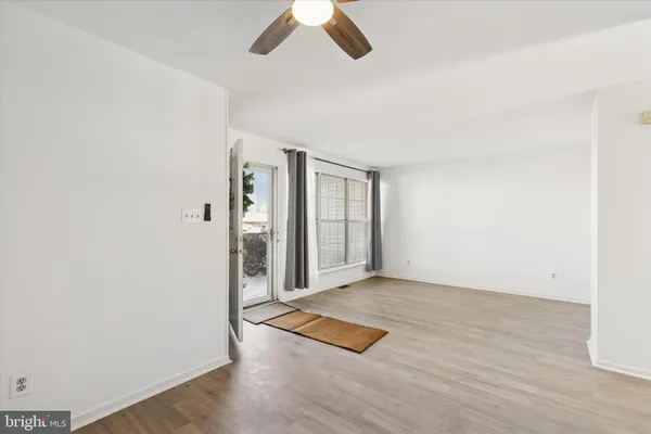 an empty room with wooden floor cabinet and windows