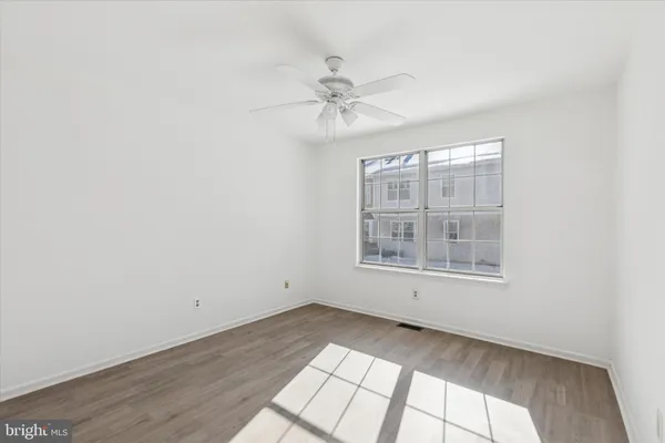 an empty room with wooden floor fan and windows