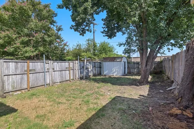 a view of a house with a yard and a large tree