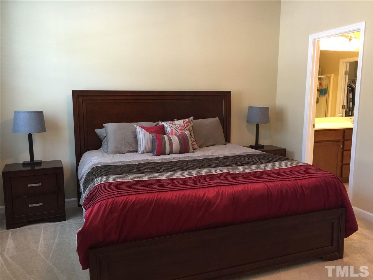 721 Wickham Ridge Road Apex, NC 27539 - Photo 11 of 25 a bedroom with a bed and a lamp