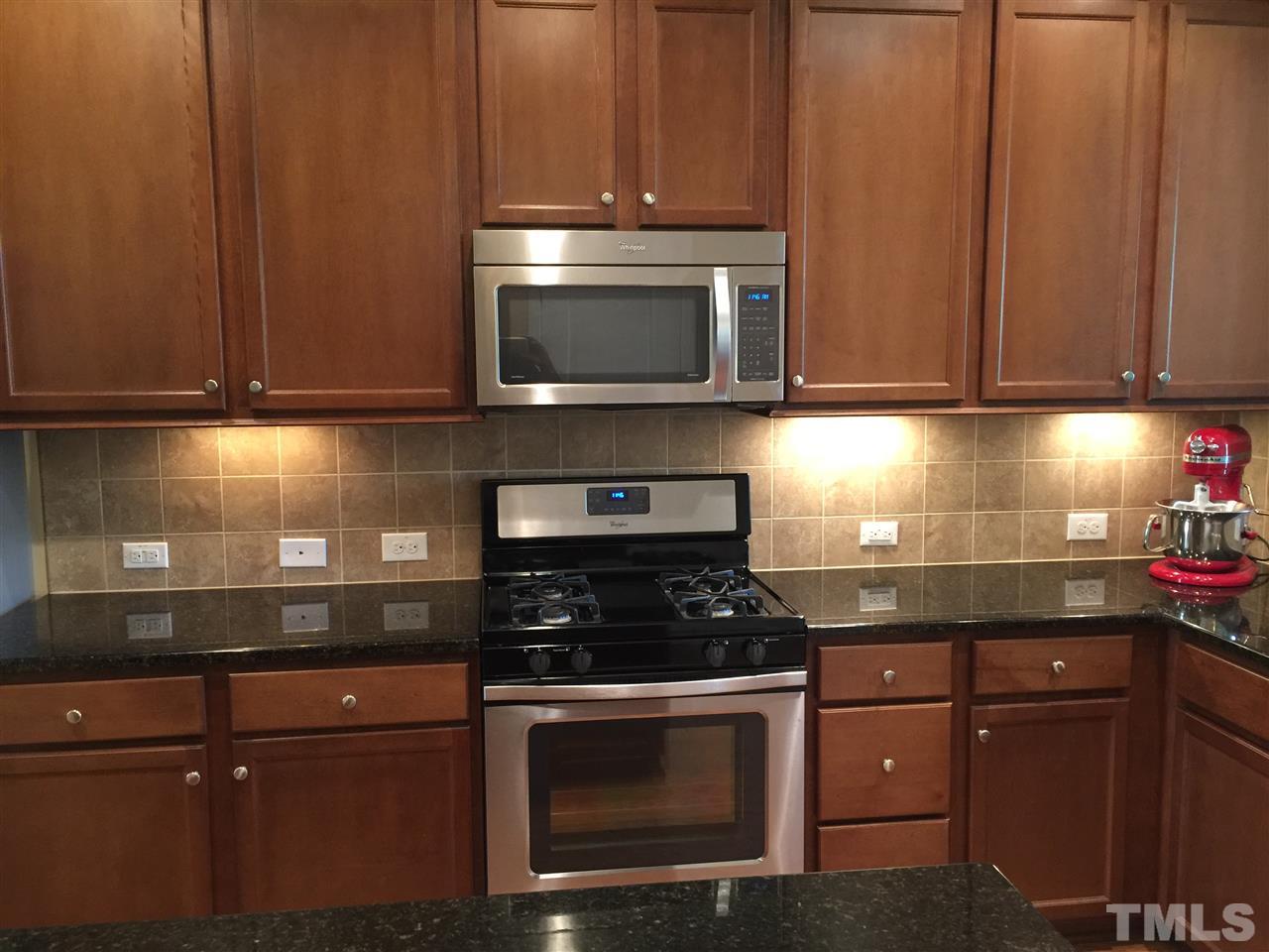 721 Wickham Ridge Road Apex, NC 27539 - Photo 7 of 25 a kitchen with granite countertop wood cabinets and stainless steel appliances
