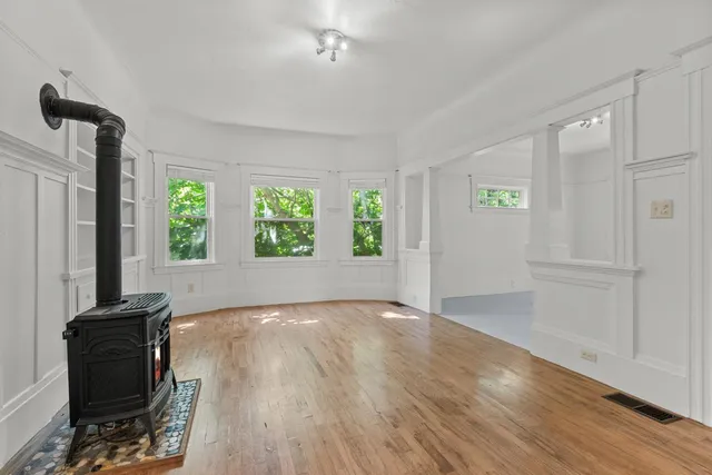 a view of an empty room with a window and wooden floor