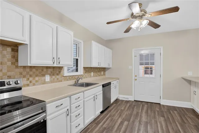 a kitchen with a sink cabinets stainless steel appliances and a window