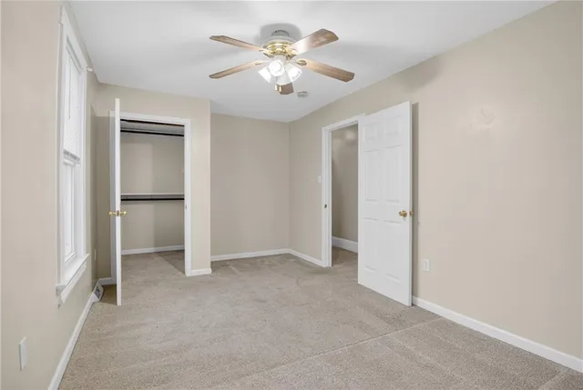 an empty room with closet and a ceiling fan