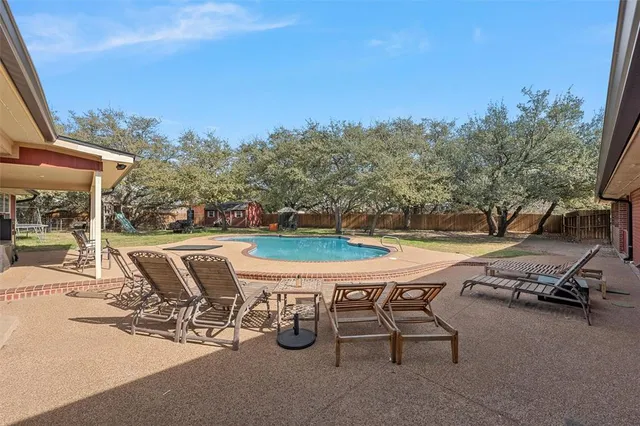 a view of a swimming pool with lawn chairs under an umbrella