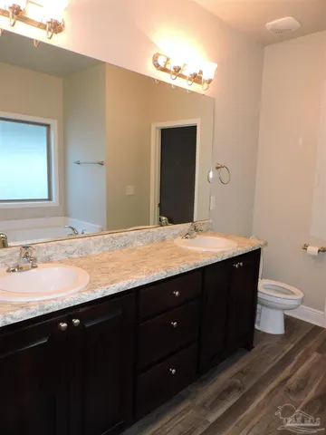 a bathroom with a granite countertop sink toilet a large mirror and a bathtub