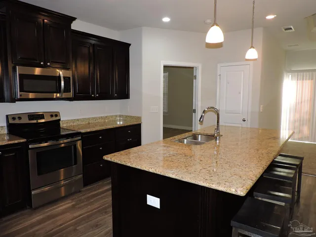 a kitchen with kitchen island granite countertop stainless steel appliances and wooden cabinets