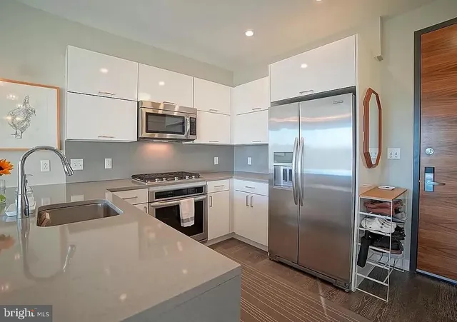 a kitchen with stainless steel appliances granite countertop a refrigerator a stove and a sink with wooden floor