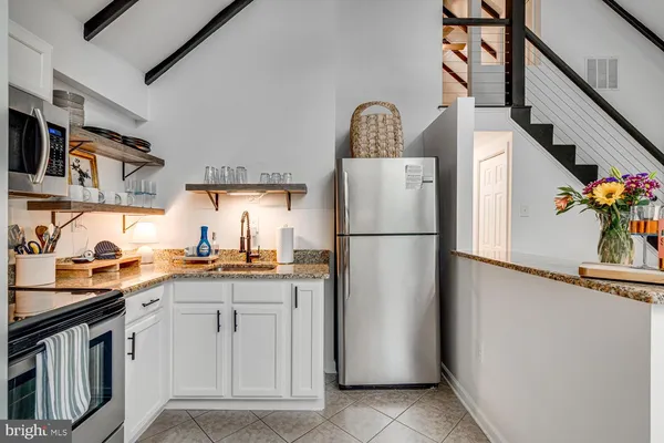 a living room with stainless steel appliances furniture a rug and a view of kitchen