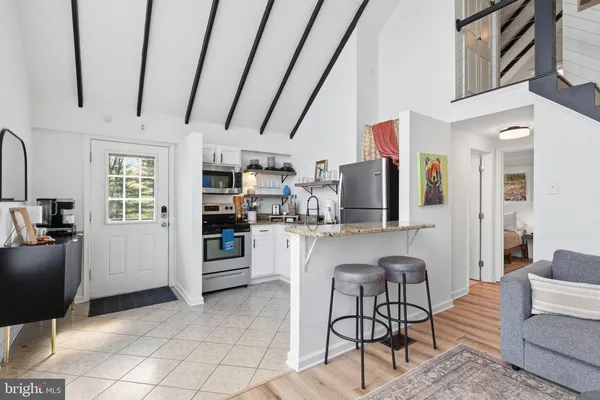 a living room with stainless steel appliances furniture a rug and a view of kitchen