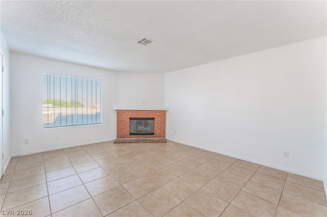 2257 Exeter Drive, Unit B Las Vegas, NV 89156 - Photo 13 of 39 Unfurnished living room featuring a textured ceiling, a fireplace, and light tile patterned flooring