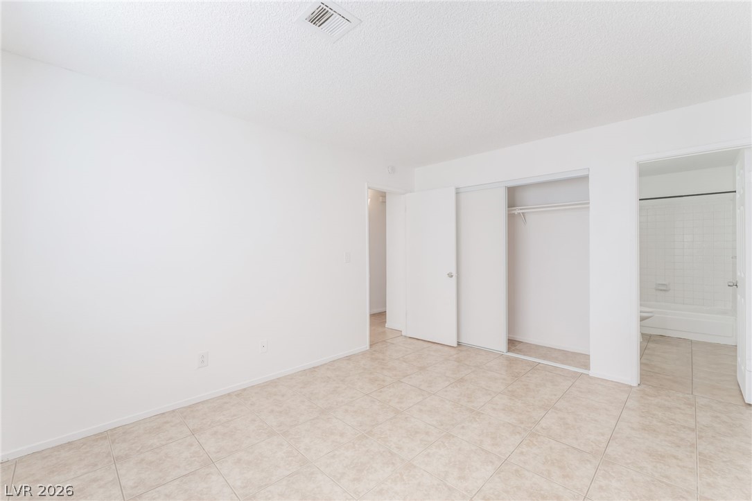 2257 Exeter Drive, Unit B Las Vegas, NV 89156 - Photo 28 of 39 Unfurnished bedroom featuring a closet, connected bathroom, a textured ceiling, and light tile patterned floors