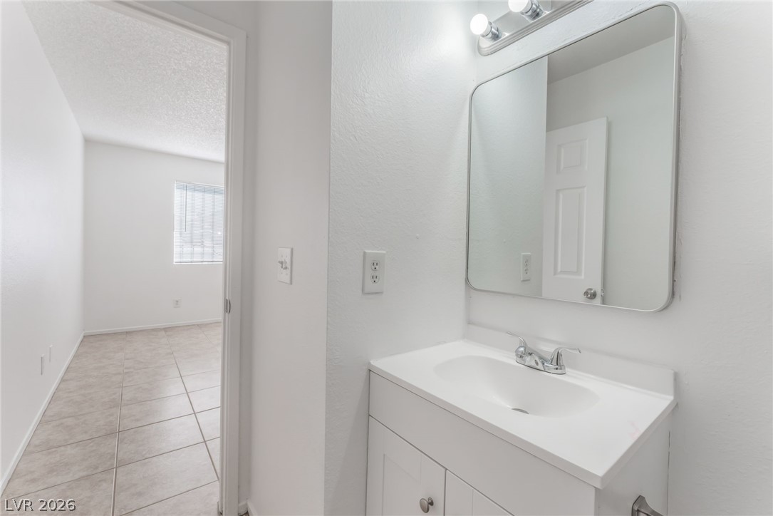 2257 Exeter Drive, Unit B Las Vegas, NV 89156 - Photo 31 of 39 Half bath with vanity, light tile patterned flooring, and a textured ceiling