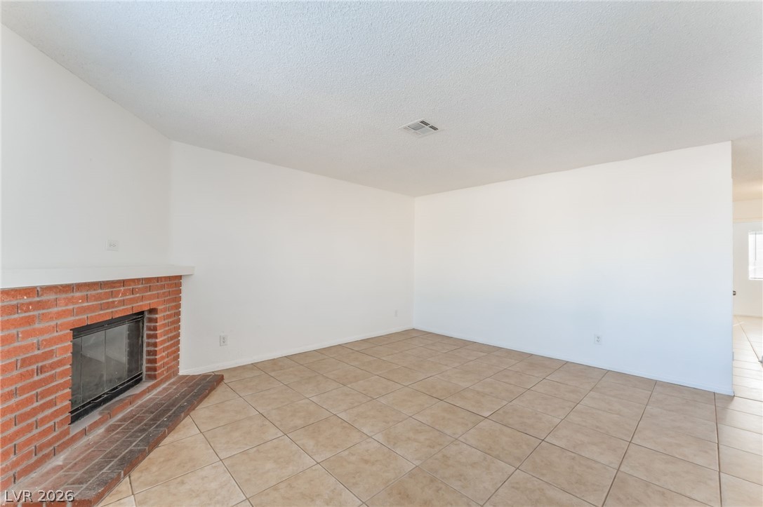 2257 Exeter Drive, Unit B Las Vegas, NV 89156 - Photo 8 of 39 Unfurnished living room with a fireplace, light tile patterned floors, and a textured ceiling
