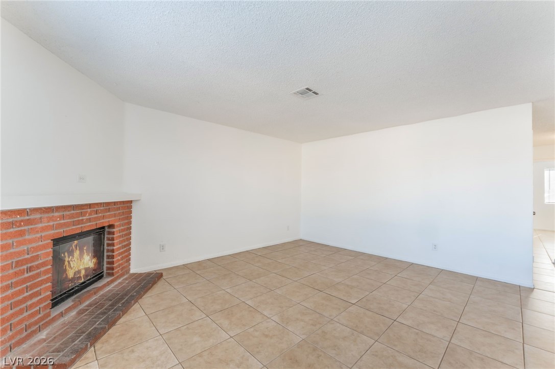 2257 Exeter Drive, Unit B Las Vegas, NV 89156 - Photo 9 of 39 Unfurnished living room with a fireplace, a textured ceiling, and light tile patterned flooring
