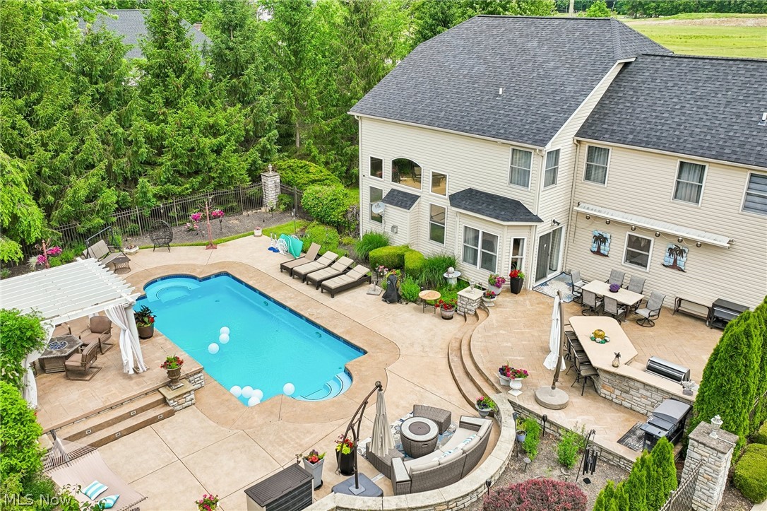 8874 Sharp Road Olmsted Falls, OH 44138 - Photo 22 of 42 Expansive backyard featuring a large in-ground swimming pool, a dedicated pergola-covered patio, and extensive stamped concrete hardscaping