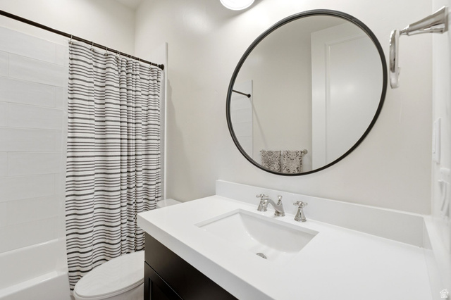 71 Farm Road Midway, UT 84049 - Photo 75 of 92 Bathroom featuring a built-in tub with white subway tile surround, a dark wood-finish vanity, white countertop with integrated sink, and a circular black-framed mirror