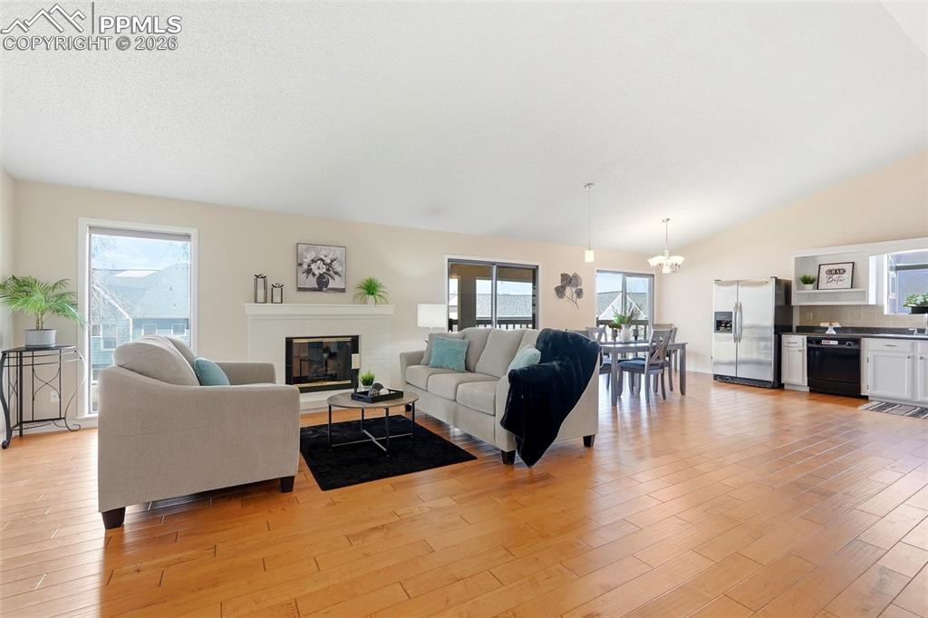 240 Bennington Drive Colorado Springs, CO 80906 - Photo 14 of 44 This bright interior features hardwood flooring, a white fireplace, and vaulted ceilings