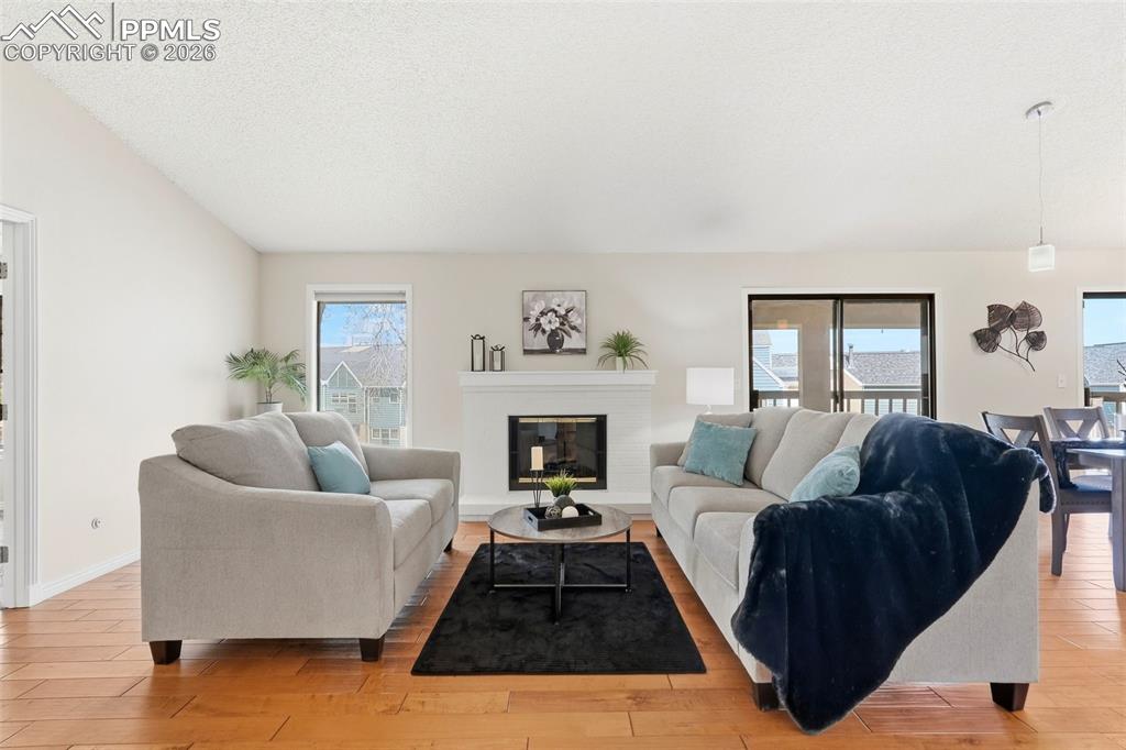 240 Bennington Drive Colorado Springs, CO 80906 - Photo 15 of 44 Living room featuring hardwood floors, a white fireplace with a mantel, and a sliding glass door providing external views
