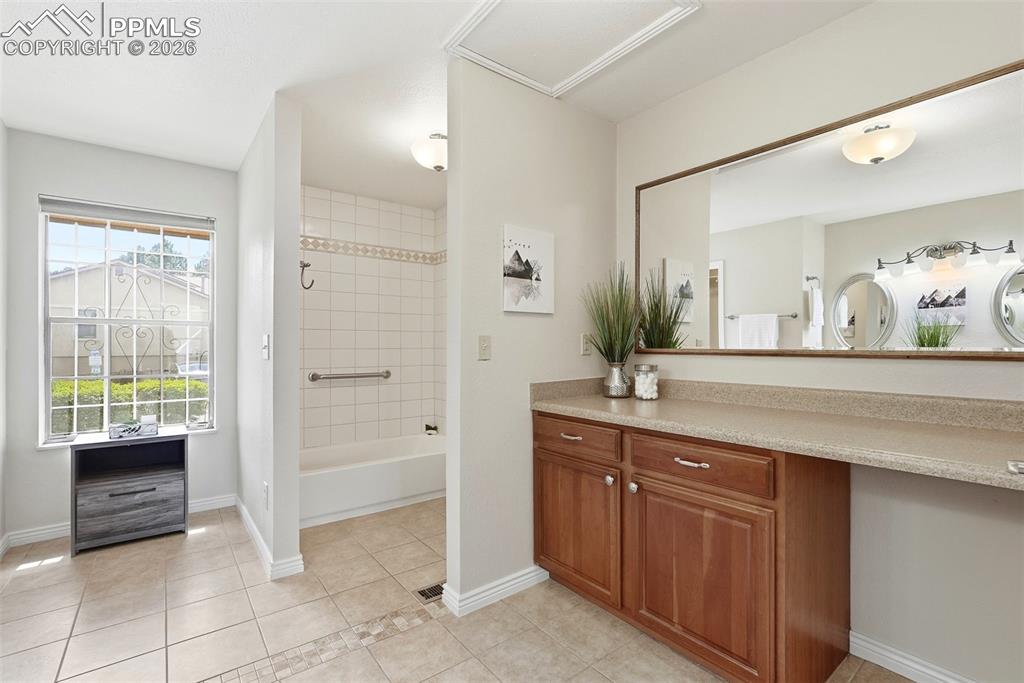 240 Bennington Drive Colorado Springs, CO 80906 - Photo 20 of 44 This bathroom features a spacious vanity with wood cabinetry and a large mirror, alongside a window providing natural light