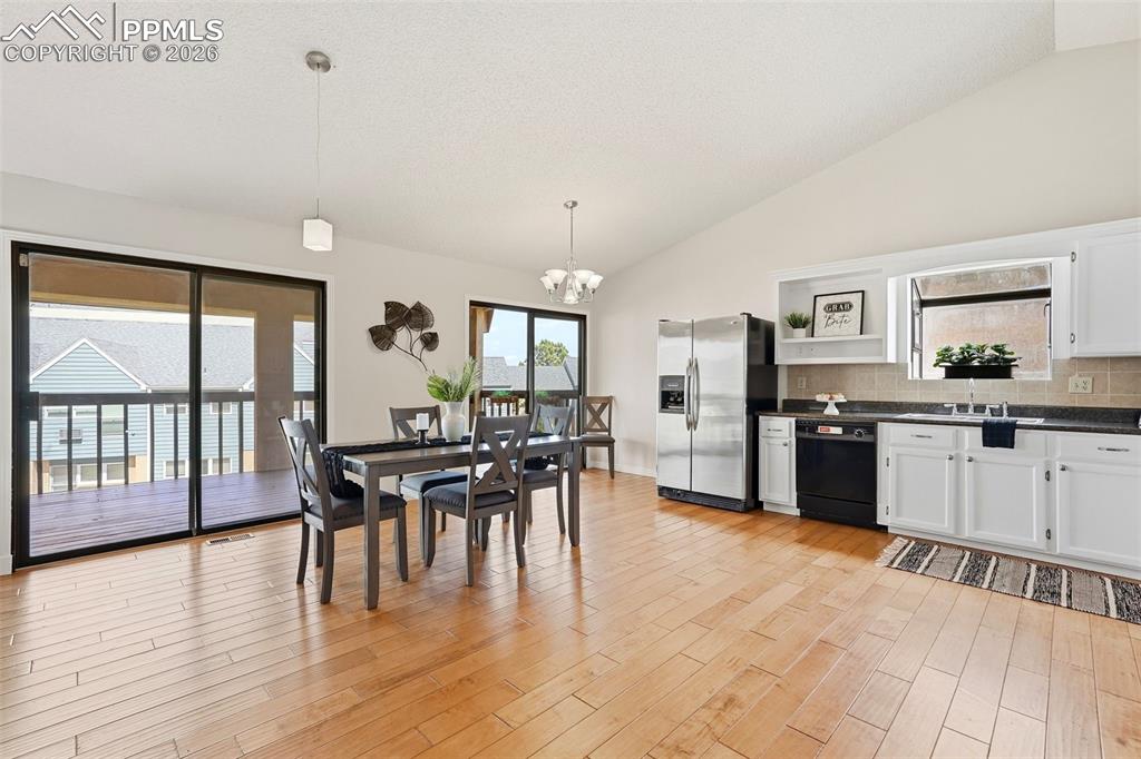 240 Bennington Drive Colorado Springs, CO 80906 - Photo 2 of 44 Open concept living space featuring hardwood floors, a kitchen with white cabinetry and stainless steel appliances, and sliding glass doors leading to an outdoor deck
