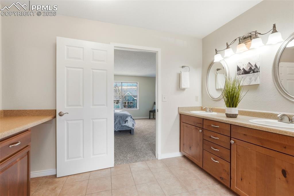 240 Bennington Drive Colorado Springs, CO 80906 - Photo 22 of 44 The property features a vanity area with light-colored countertops, two sinks, and wood cabinetry