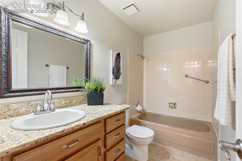 240 Bennington Drive Colorado Springs, CO 80906 - Photo 23 of 44 Bathroom featuring a light-colored granite countertop, wood vanity with brushed nickel hardware, a large mirror with an ornate frame, and a bathtub with shower