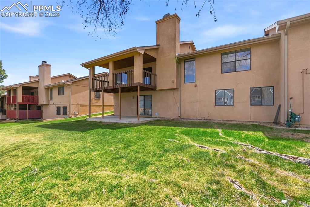 240 Bennington Drive Colorado Springs, CO 80906 - Photo 34 of 44 The property features a private yard with a lawn, a ground-level patio, and an upper-level balcony with wooden railings