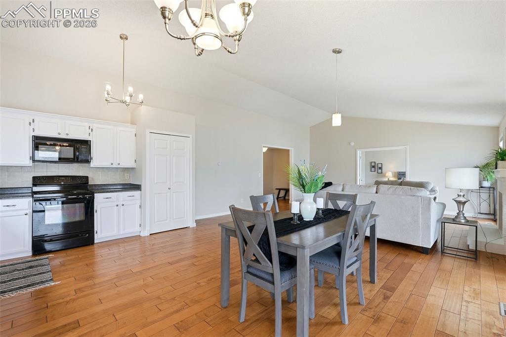 240 Bennington Drive Colorado Springs, CO 80906 - Photo 10 of 44 The property features an open concept kitchen and living area, complete with hardwood floors, a kitchen with white cabinetry and black appliances, and a dining area with a modern light fixture