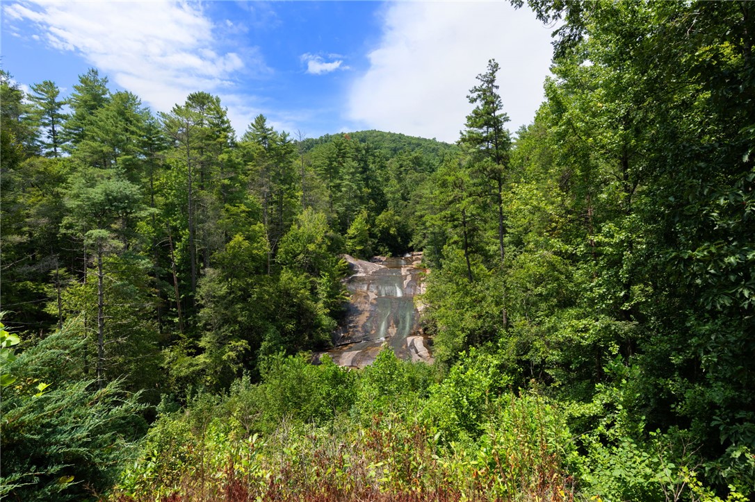 300 Whispering Falls Road Pickens, SC 29671 - Photo 39 of 41 Lush forest canopies frame a peaceful mountain waterfall under blue skies.