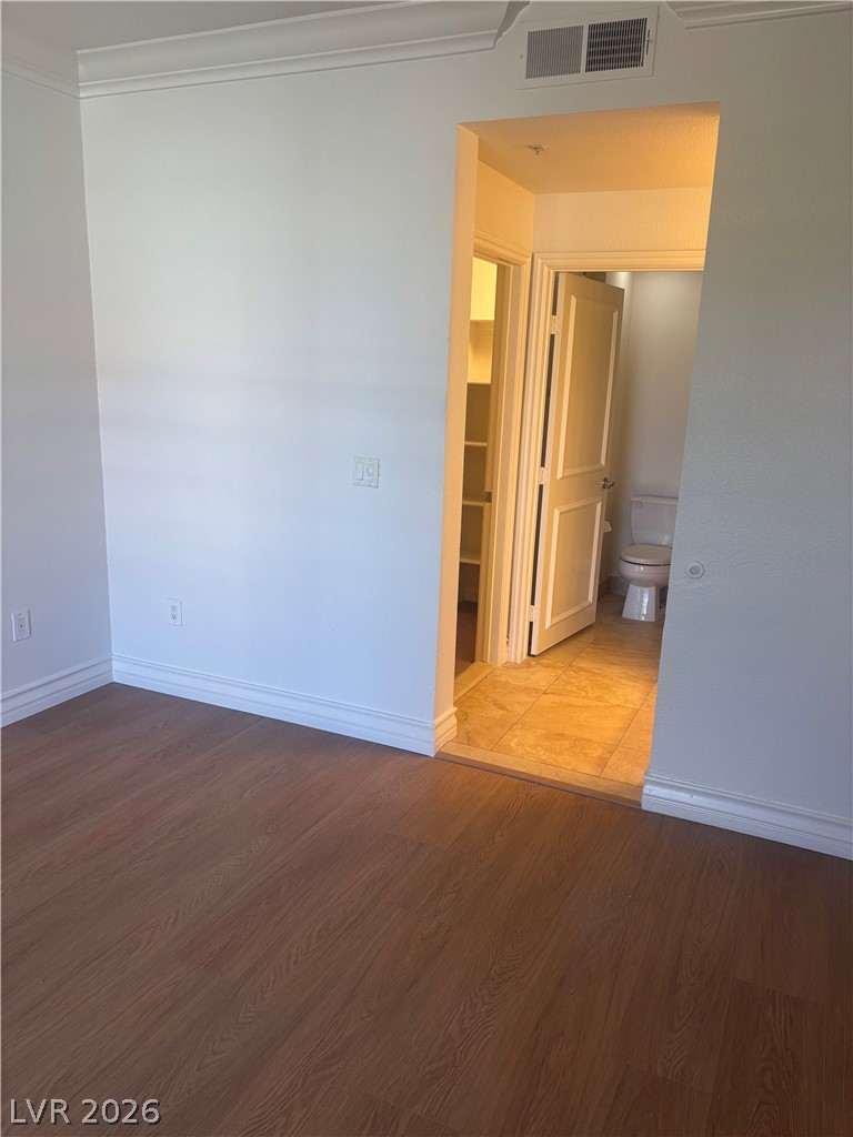 210 East Flamingo Road, Unit 123 Las Vegas, NV 89169 - Photo 9 of 17 Rich wood floors and elegant crown molding flow seamlessly toward an adjacent private bathroom.