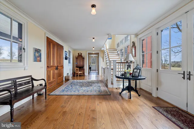 a view of a hallway with wooden floor and a bathroom