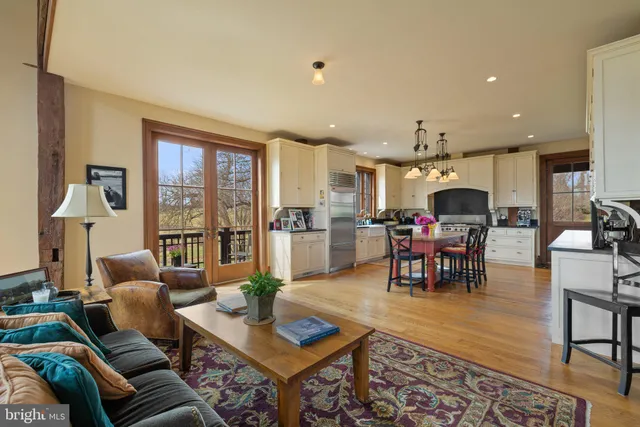 a kitchen with stainless steel appliances kitchen island granite countertop a sink dishwasher a dining table and chairs with wooden floor