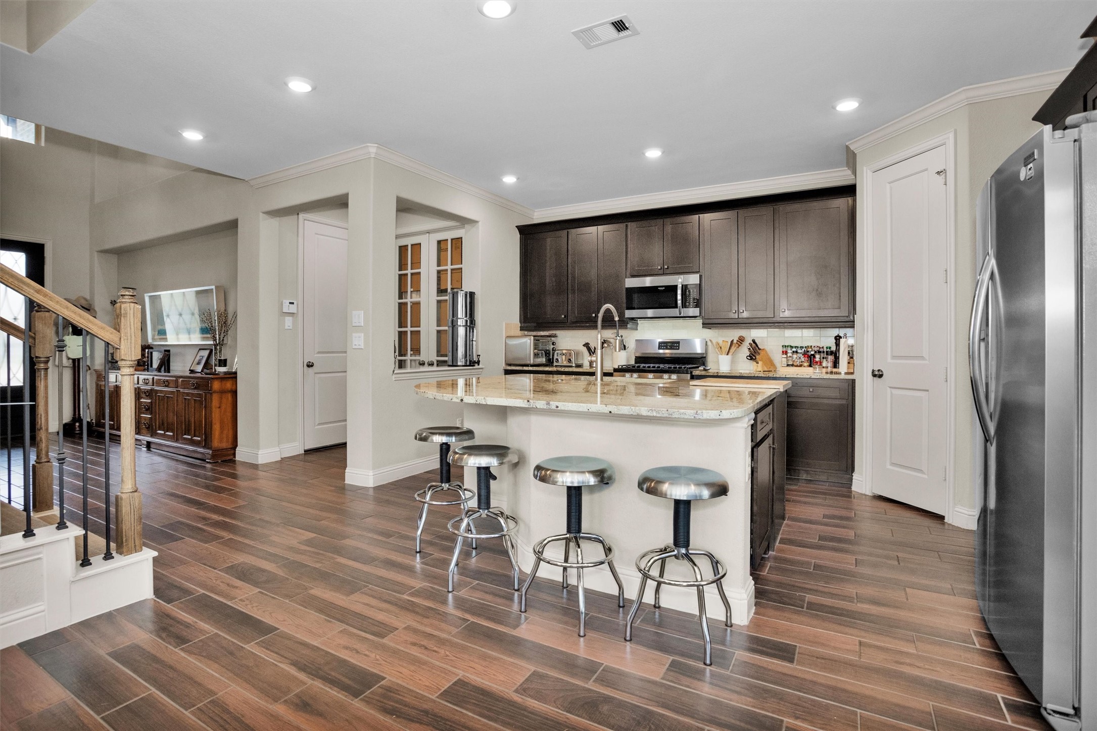 7451 Bethpage Lane Spring, TX 77389 - Photo 9 of 31 a kitchen with stainless steel appliances kitchen island granite countertop a refrigerator a stove a microwave oven a dining table and chairs