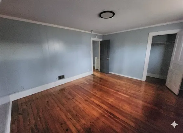 a view of empty room with wooden floor
