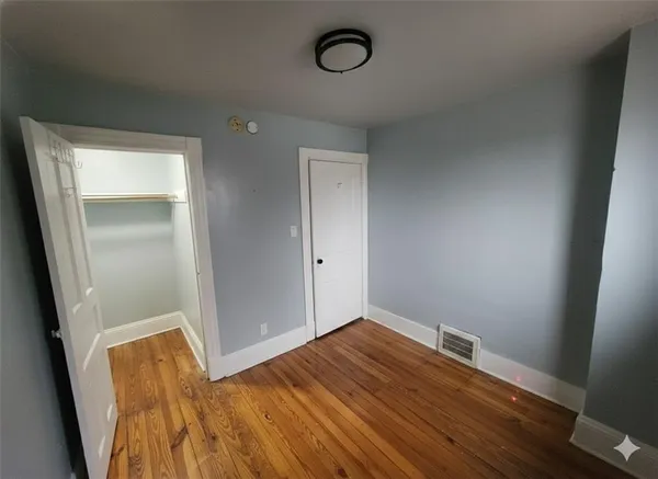 an empty room with wooden floor and mirror