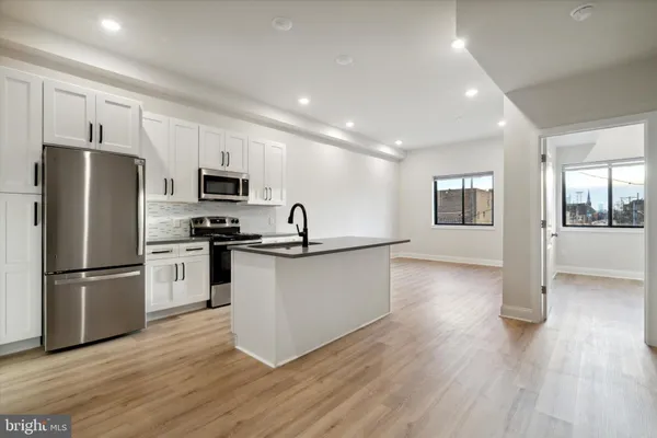 a kitchen with granite countertop a refrigerator and a stove top oven