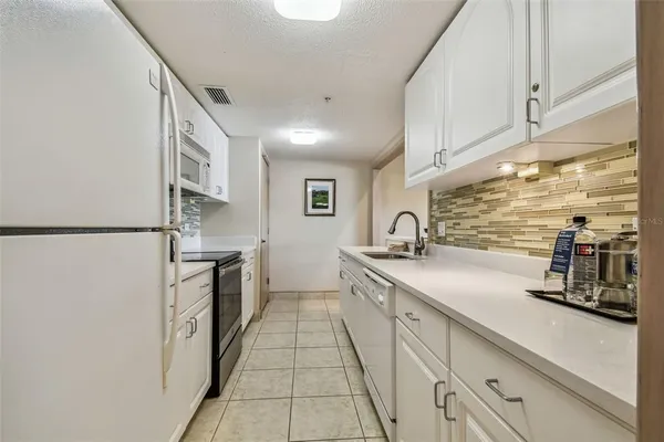 a large white kitchen with stainless steel appliances granite countertop a sink and cabinets