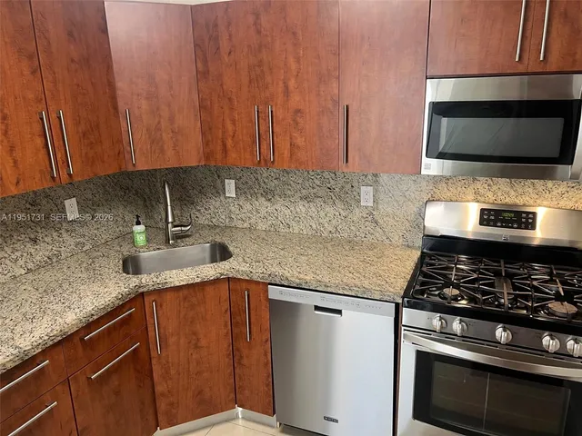 a kitchen with granite countertop a sink stove and microwave