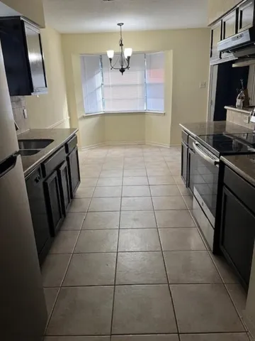 a kitchen with granite countertop a stove a sink and a counter top space