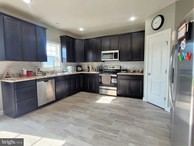 a kitchen with stainless steel appliances granite countertop a stove top oven a sink dishwasher and a refrigerator with cabinets