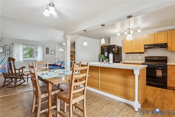 a kitchen with stainless steel appliances kitchen island granite countertop a stove top oven a dining table and chairs with wooden floor