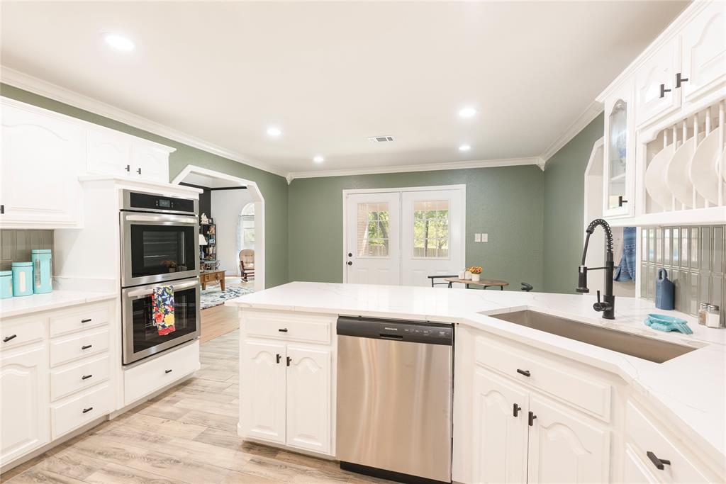 2020 Arbor Bend Road Bonham, TX 75418 - Photo 13 of 40 Kitchen with stainless steel appliances, ,white cabinetry, a peninsula, light quartz countertops, and crown molding