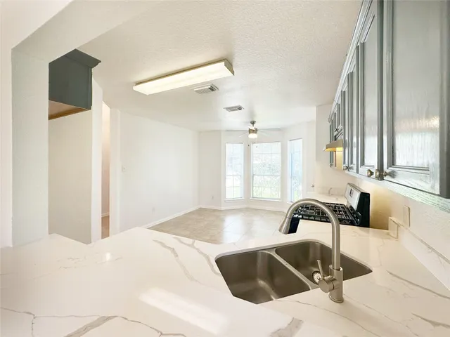 a kitchen with granite countertop a stove a sink and a refrigerator