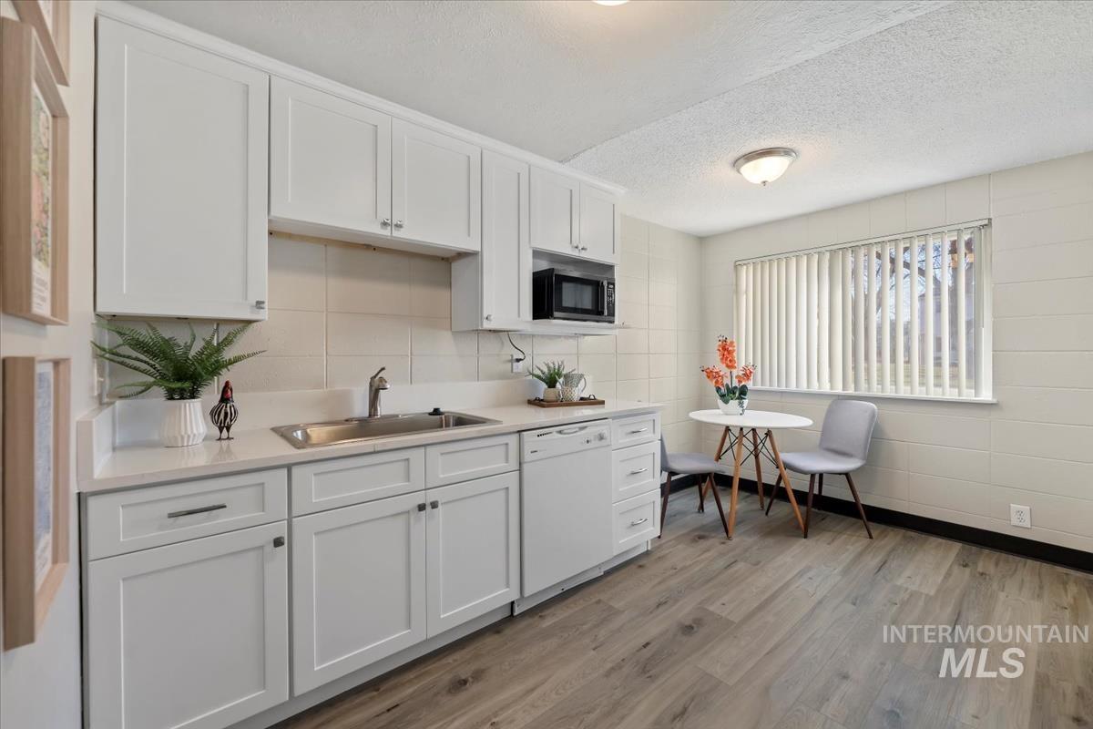 952 South Curtis Road Boise, ID 83705 - Photo 12 of 37 Kitchen featuring white cabinets, a textured ceiling, dishwasher, and light wood-style floors