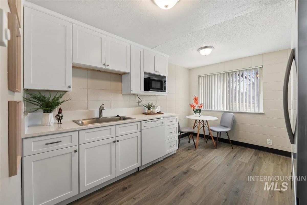 952 South Curtis Road Boise, ID 83705 - Photo 13 of 37 Kitchen with white cabinets, light countertops, freestanding refrigerator, a textured ceiling, and white dishwasher