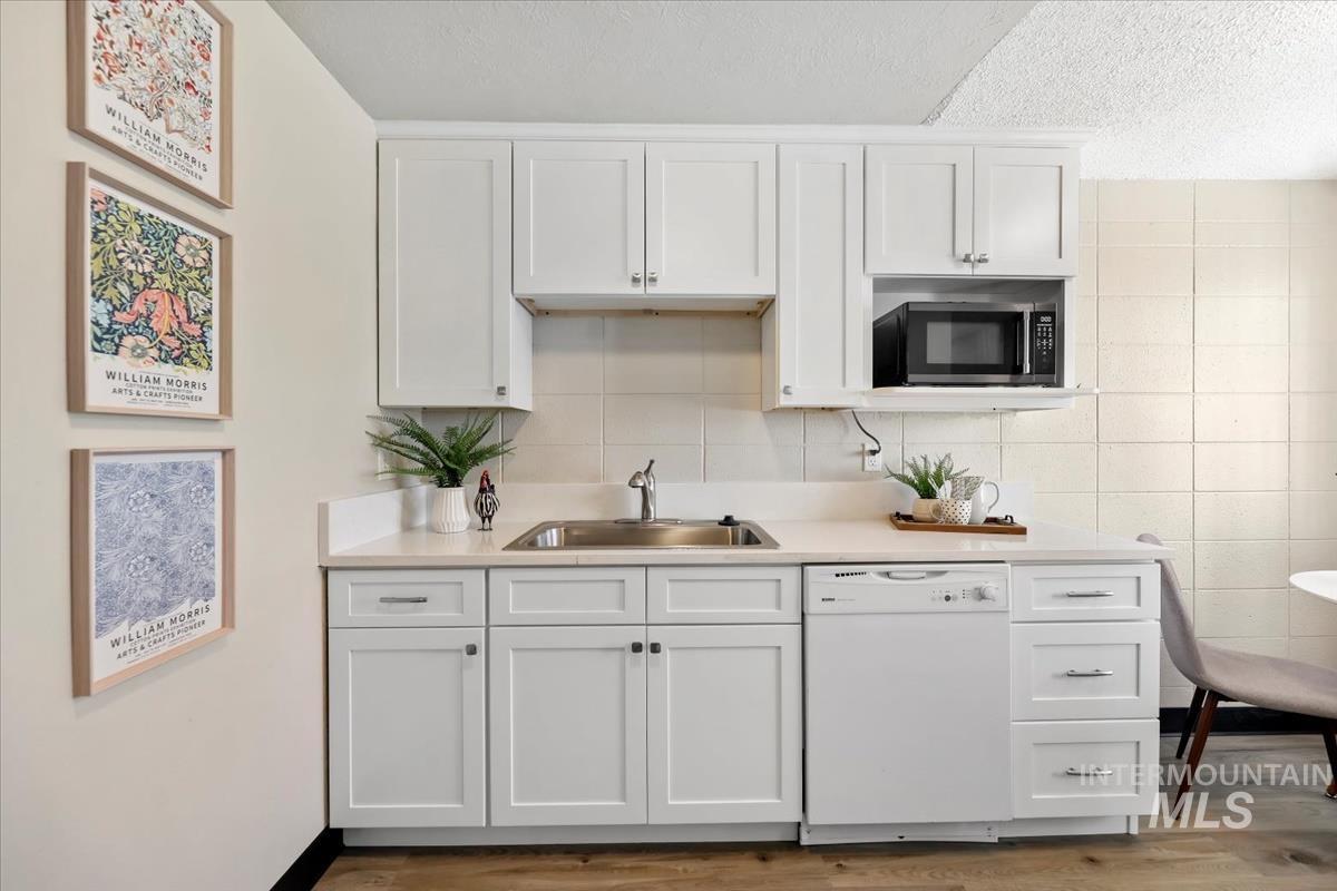 952 South Curtis Road Boise, ID 83705 - Photo 14 of 37 Kitchen with light countertops, dishwasher, white cabinets, a textured ceiling, and light wood-style flooring