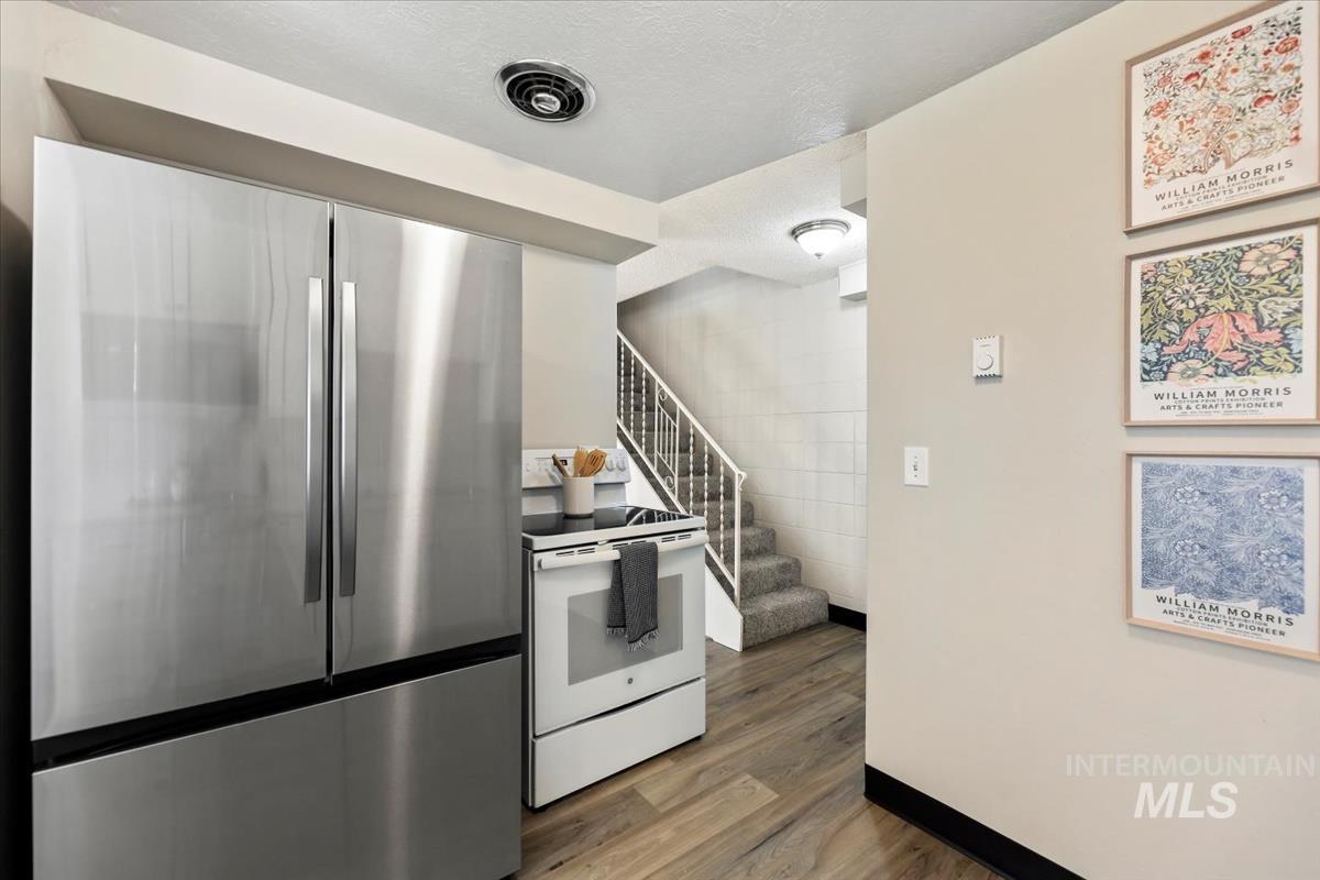 952 South Curtis Road Boise, ID 83705 - Photo 22 of 37 Kitchen with freestanding refrigerator, white electric stove, dark wood-type flooring, and a textured ceiling