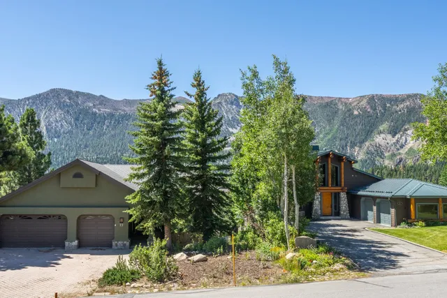 a front view of a house with a yard and mountain view